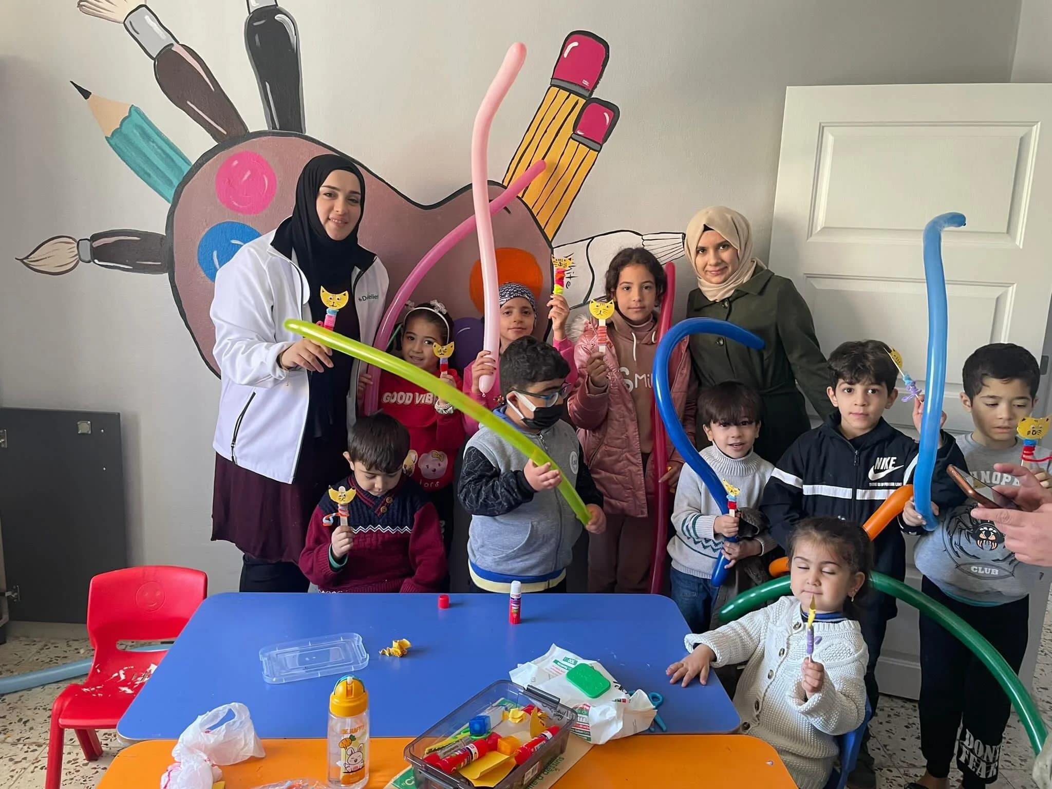 Deen Relief carers leading a balloon and arts activity with children at the care centre