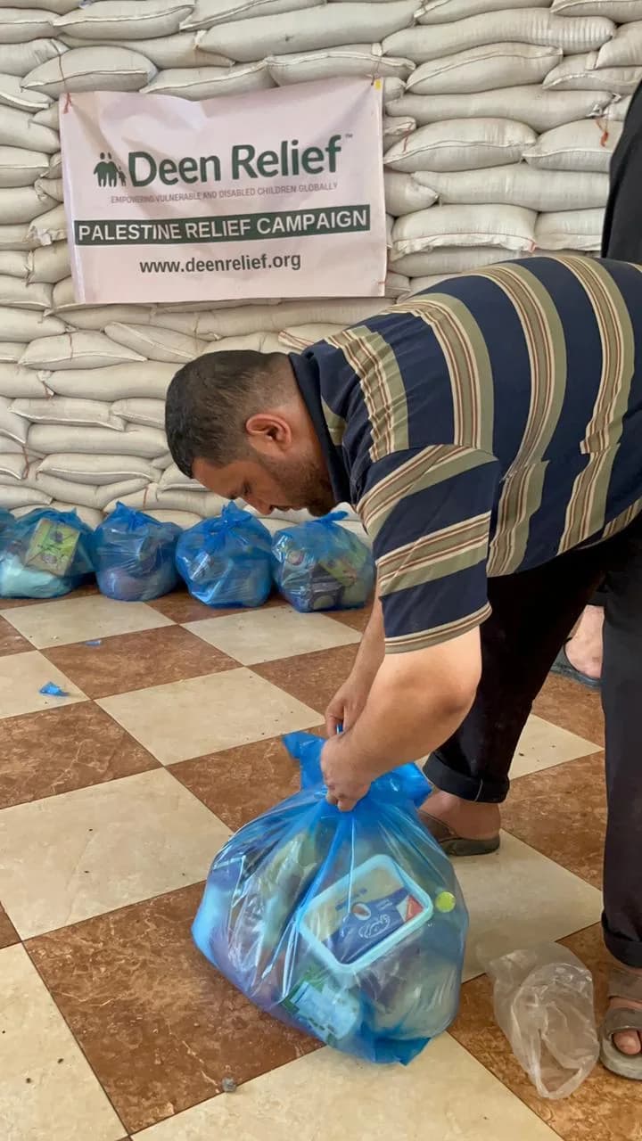 Deen Relief worker packing aid supplies in front of Deen Relief Palestine Relief Campaign banner