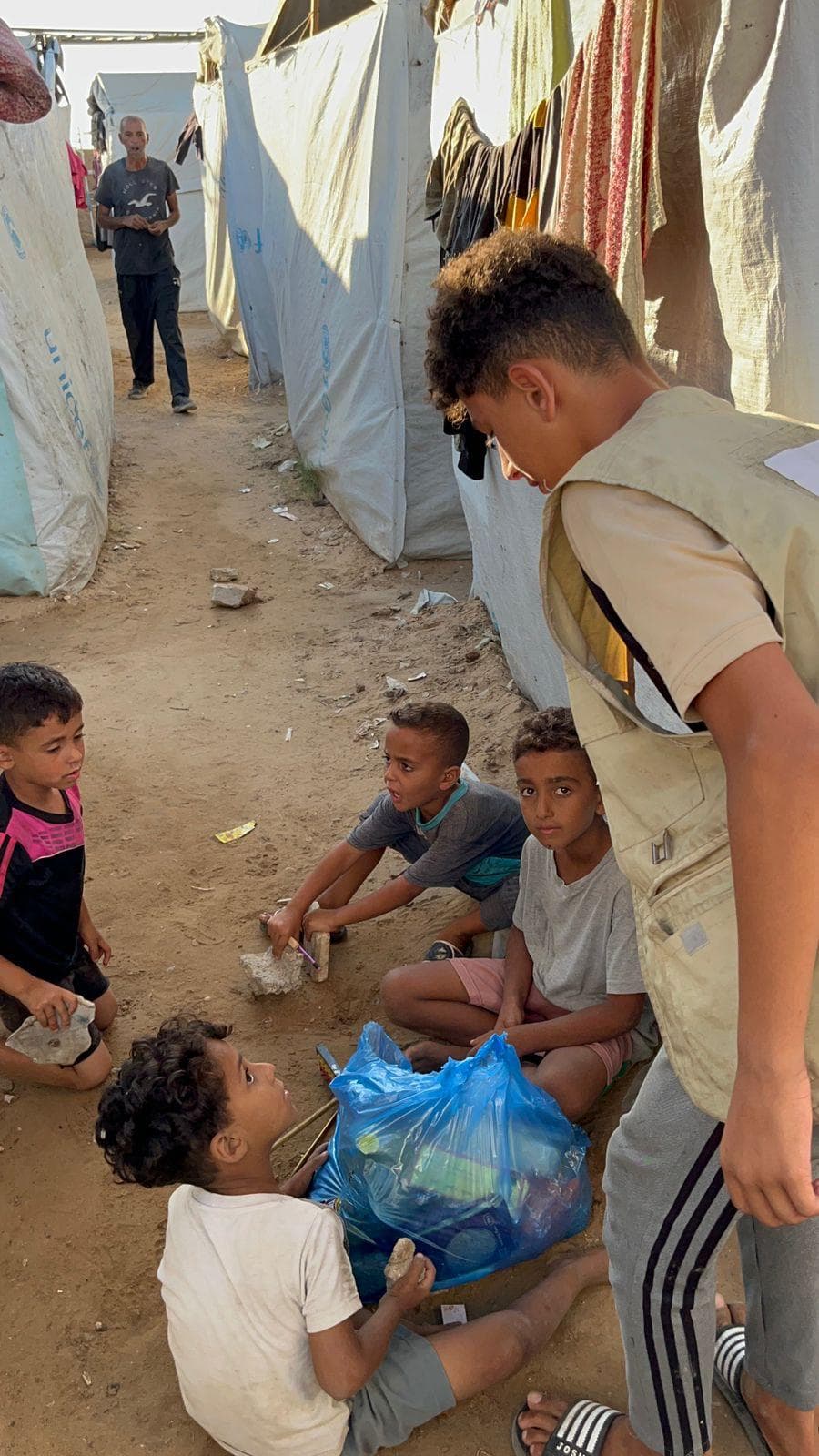 Deen Relief field worker delivering an aid package to children in a Gaza displacement camp