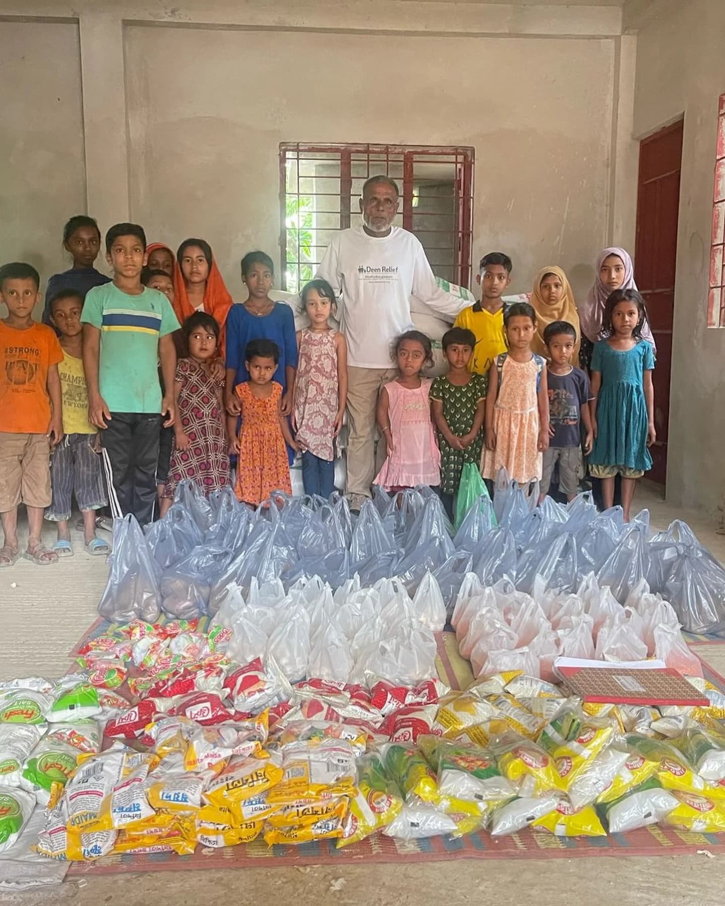 A Deen Relief field worker with a large group of children and a major food aid distribution at a Bangladesh community centre