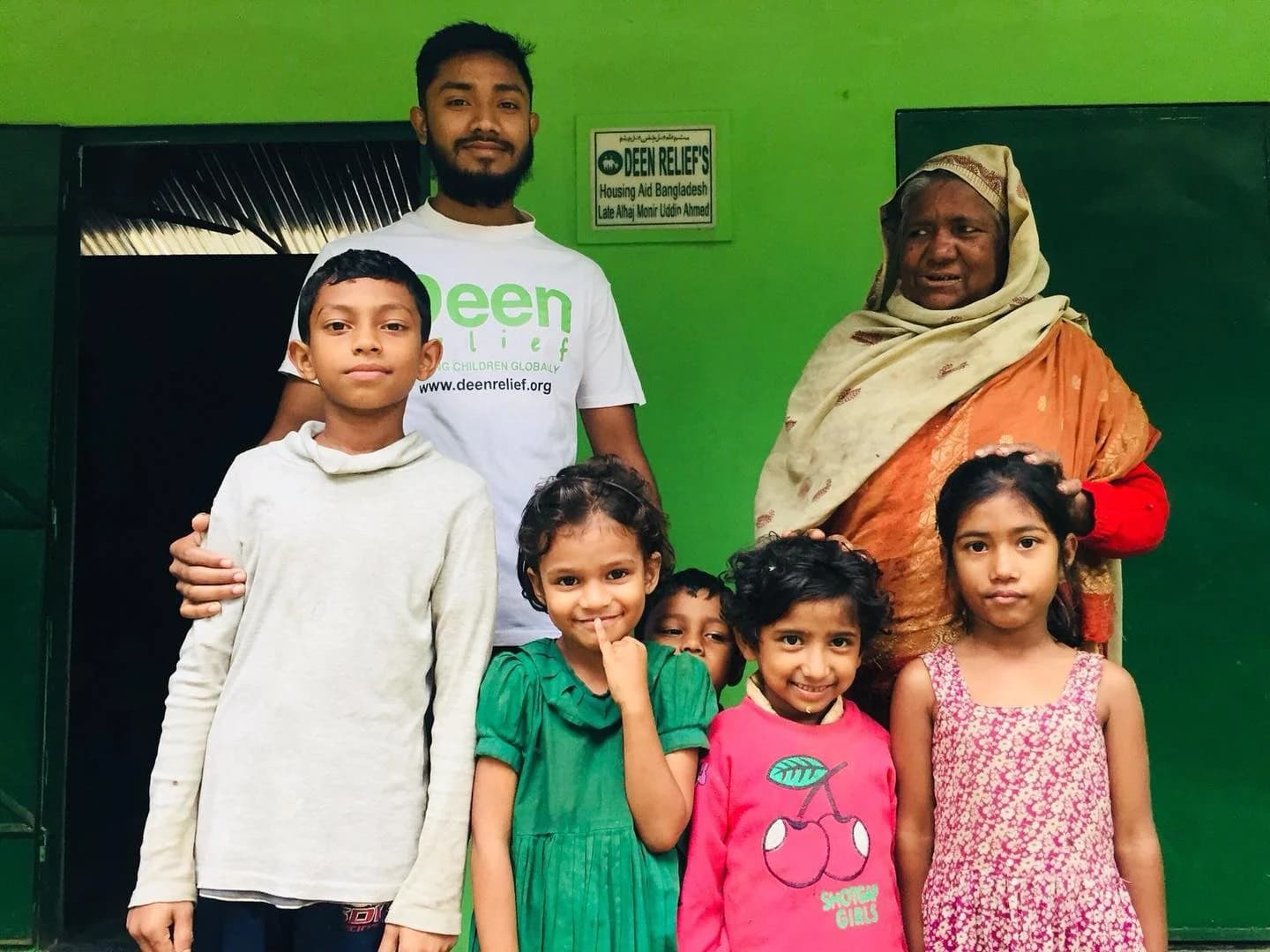 Deen Relief team member with an elderly woman and five children at a Bangladesh community housing aid centre