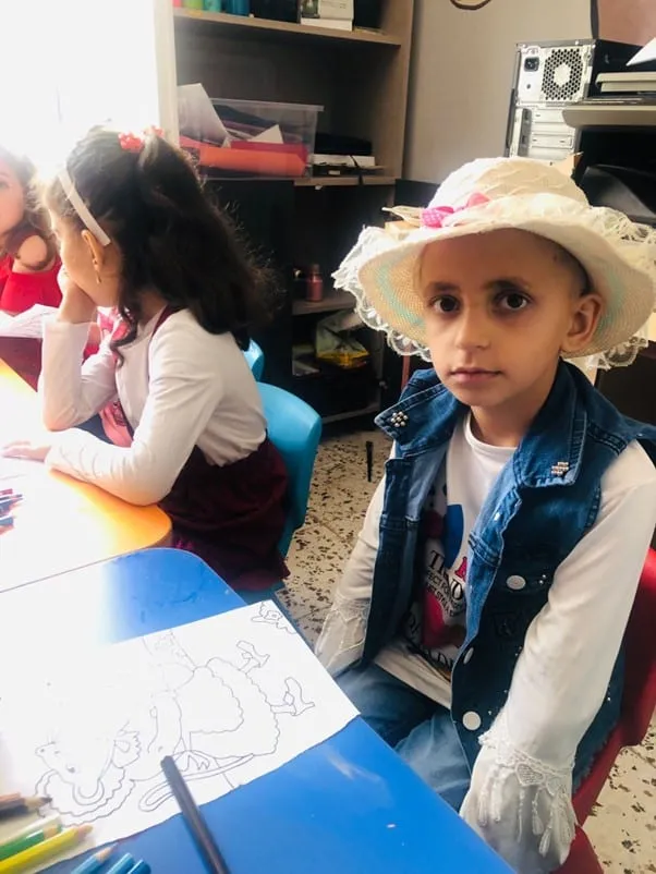 A child drawing and colouring at the Deen Relief care centre